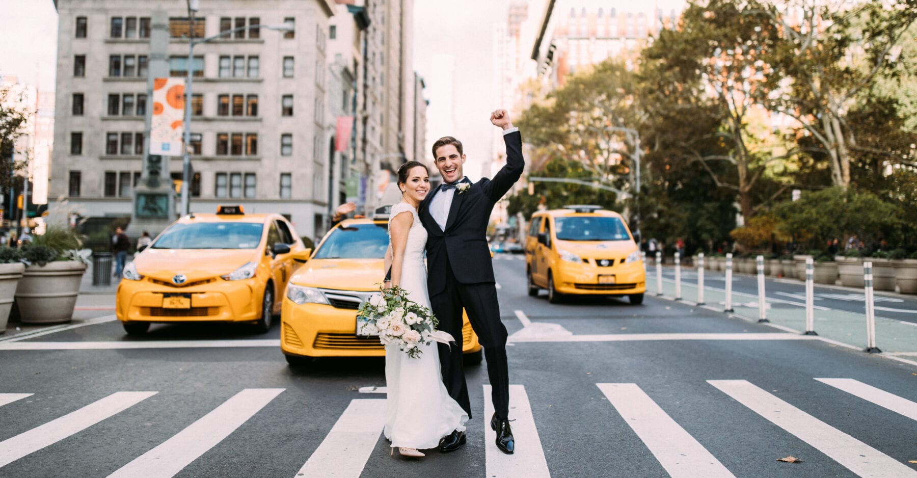 Bride and groom crossing 5th avenue with yellow cabs
